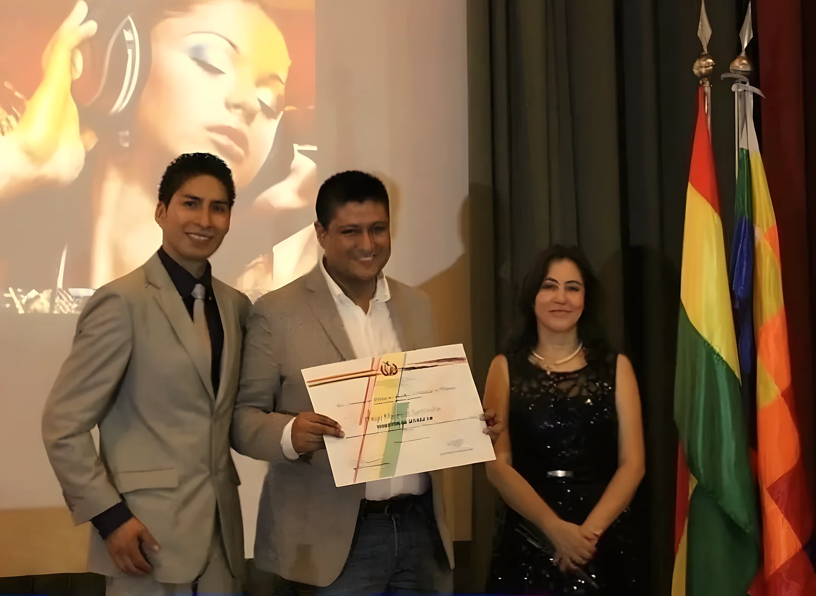 Entrega del reconocimiento del Consulado de Bolivia en Valencia a Latinos FM, con la bandera boliviana de fondo